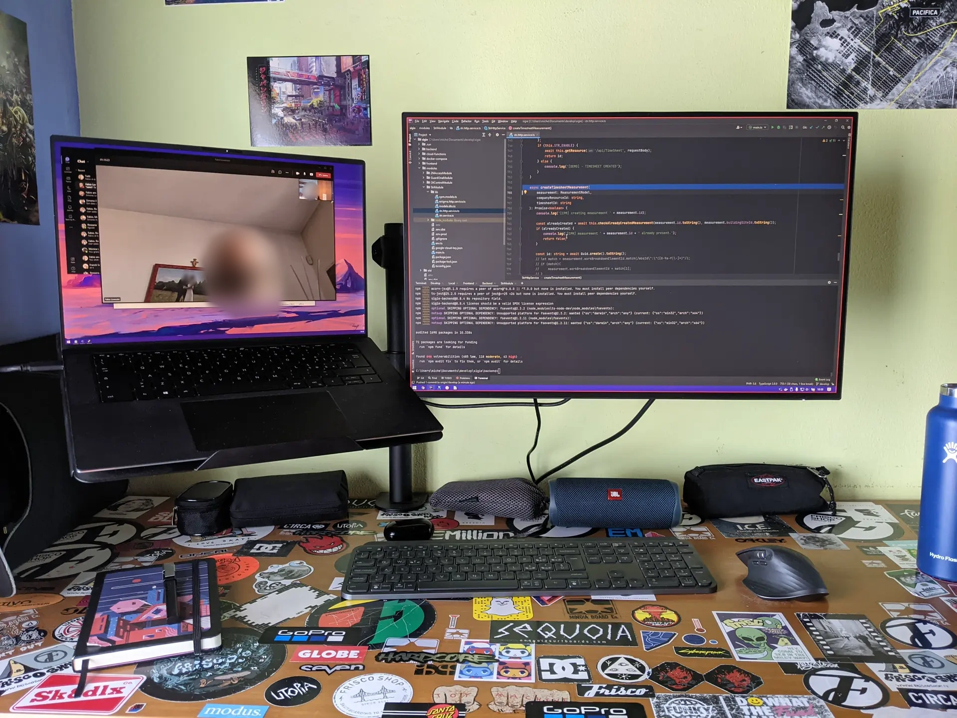 Laptop and external monitor on a desk covered in stickers