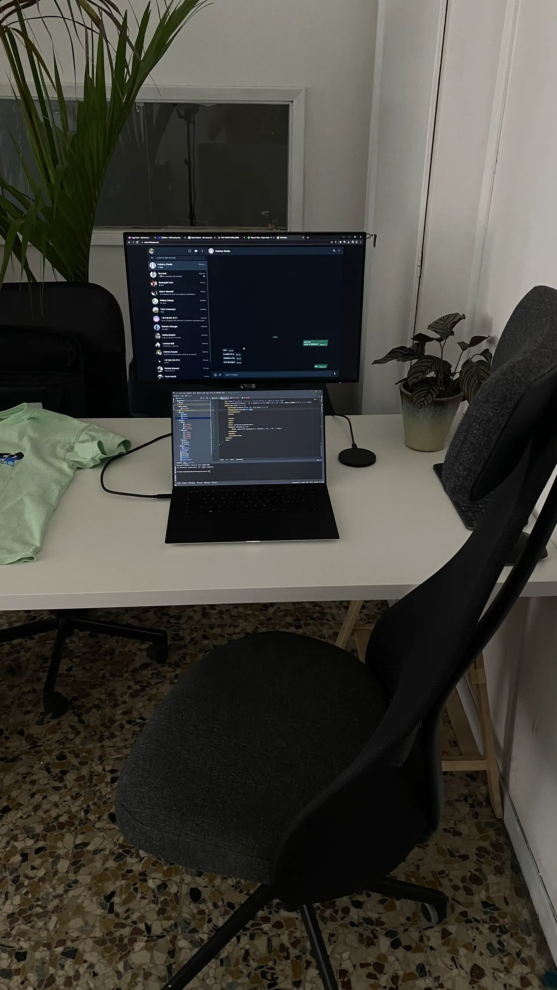 Laptop on a small white desk beside a plant